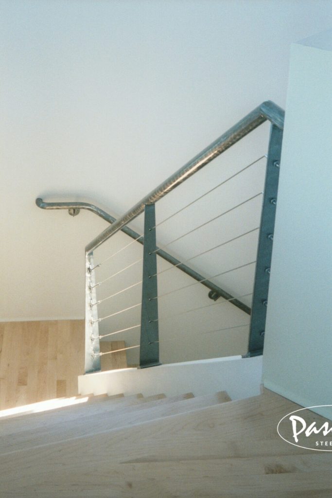 Stairway cable railing with custom attachment brackets and brushed finish
